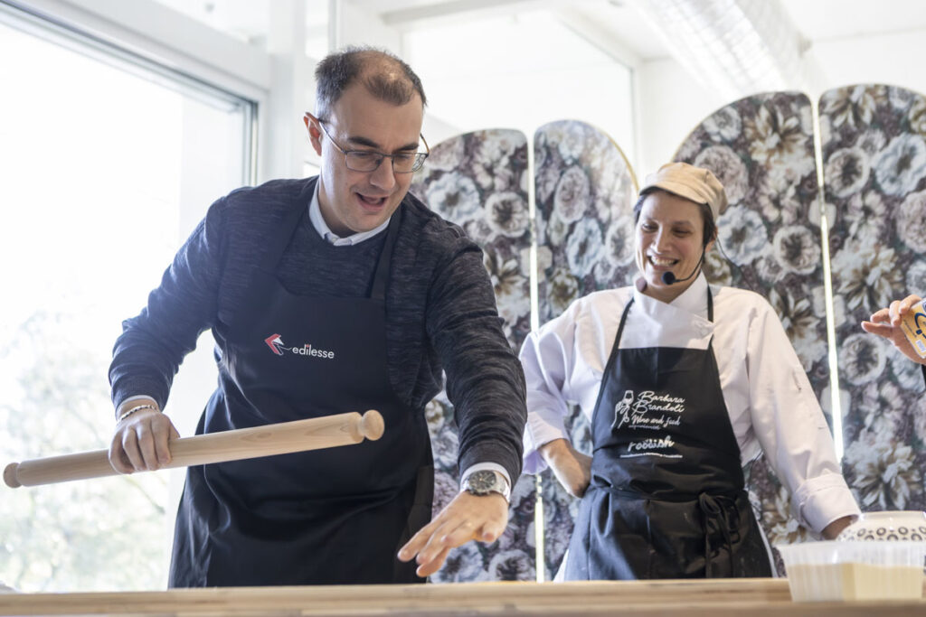 A participant learns how to roll out dough under the guidance of the sfoglina during the "Mani in Pasta" activity